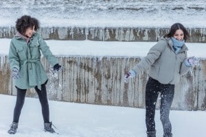 Diverse friends playing snowball fight in snowy park