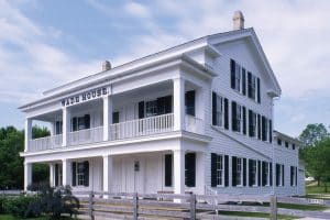 Exterior view of wade house, an 1850s stagecoach inn, surrounded by lush greenery, showcasing the historical charm and inviting ambiance of the site.