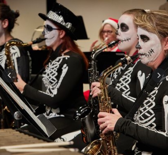 Sheboygan pops concert band members performing on stage dressed in halloween costumes.