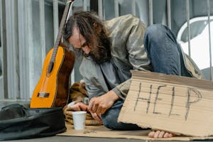 Homeless bearded man sitting on the ground