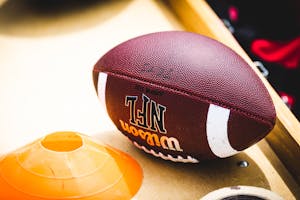 An American football placed on a training bench next to an orange training cone, ideal for sports concept.